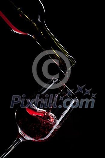 red wine pouring into wine glass isolated on black red wine pouring into wine glass isolated on black