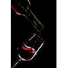 red wine pouring into wine glass isolated on black