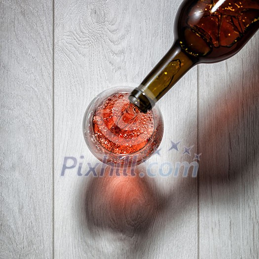 Red wine pouring into glass from bottle on white wooden table. Top view Red wine pouring into glass from bottle on white wooden table. Top view