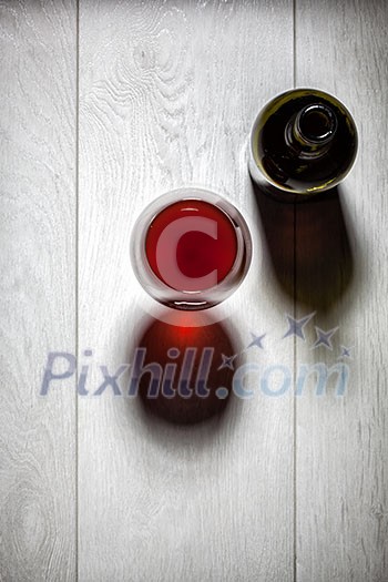 Glass and bottle of red wine with cork on white wooden table. Top view Glass and bottle of red wine with cork on white wooden table. Top view
