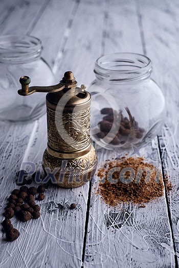 Vintage still life with brass pepper mill standing on the wooden background Vintage still life with brass pepper mill standing on the wooden background