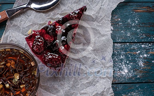 A piece of berry pie and a cup of tea on a wooden background. A piece of berry pie and a cup of tea on a wooden background.