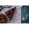 A piece of berry pie and a cup of tea on a wooden background.