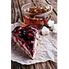A piece of berry pie and a cup of tea on a wooden background.