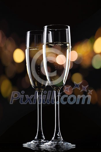 Champagne in glass on black background with color bokeh Champagne in glass on black background with color bokeh