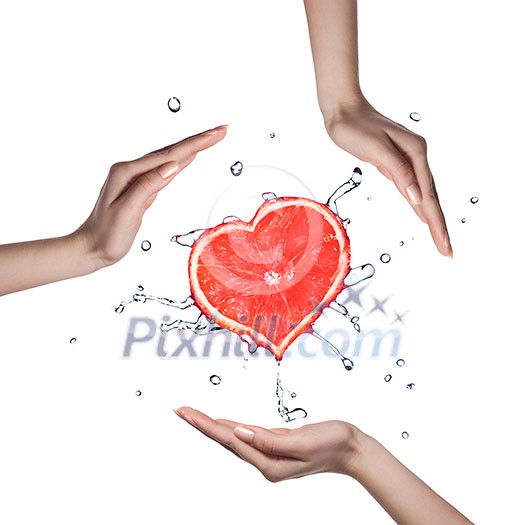 Heart of grapefruit with water splash and human hands on white Heart of grapefruit with water splash and human hands on white