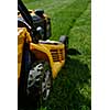 Yellow lawn mower on the green grass. Caring for a garden. Shallow depth of field.