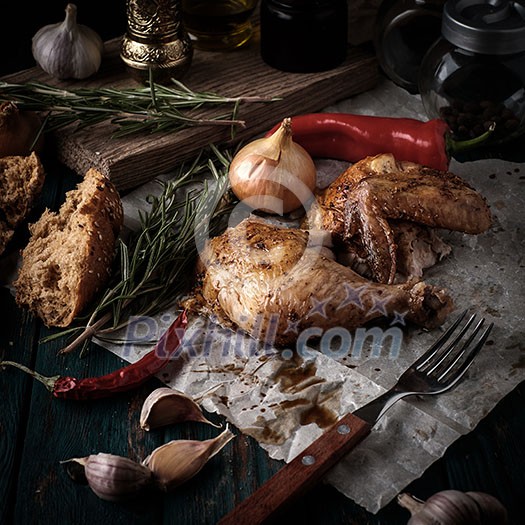 Roasted chicken with spices and herbs on a wooden table. Tasty food. Rustic style. Roasted chicken with spices and herbs on a wooden table. Tasty food. Rustic style.