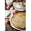 Stack of crepes and ingredients for cooking on a wooden table.