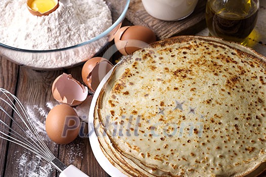 Stack of crepes and ingredients for cooking on a wooden table. Stack of crepes and ingredients for cooking on a wooden table.