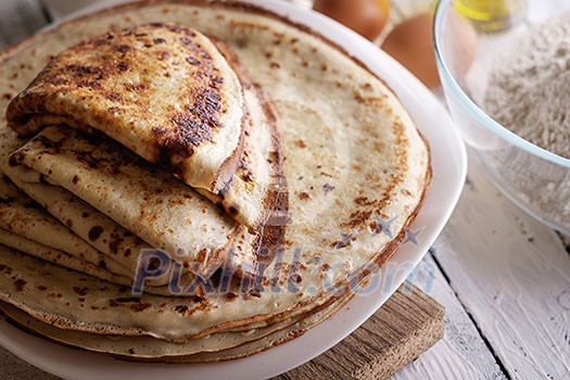 Close-up of Stack crepes and ingredients for cooking on a wooden table. Breakfast in the village. Close-up of Stack crepes and ingredients for cooking on a wooden table. Breakfast in the village.