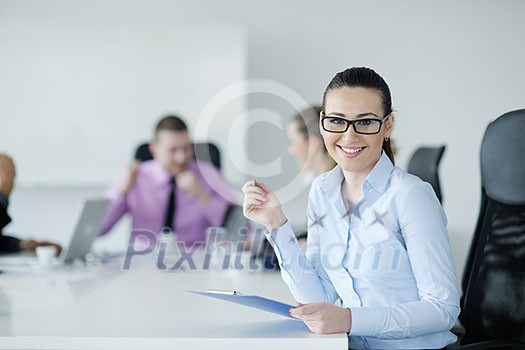 Successful business woman standing with her staff in background at modern bright office Successful business woman standing with her staff in background at modern bright office