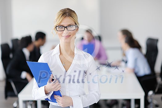 Successful business woman standing with her staff in background at modern bright office Successful business woman standing with her staff in background at modern bright office
