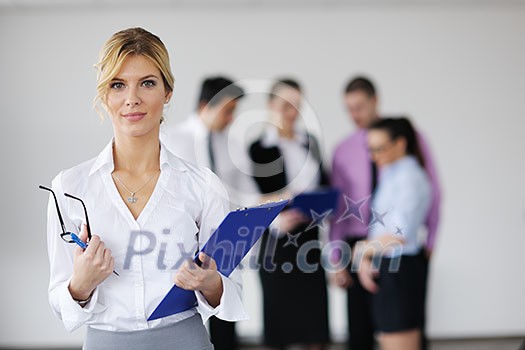 Successful business woman standing with her staff in background at modern bright office Successful business woman standing with her staff in background at modern bright office
