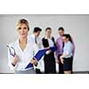 Successful business woman standing with her staff in background at modern bright office