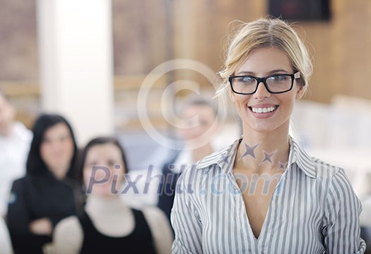 business woman standing with her staff in background at modern bright office conference room business woman standing with her staff in background at modern bright office conference room