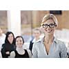business woman standing with her staff in background at modern bright office conference room