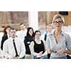 business woman standing with her staff in background at modern bright office conference room
