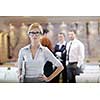 business woman standing with her staff in background at modern bright office conference room