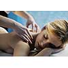 Beautiful young woman in spaand wellness. Face back and  stone massage