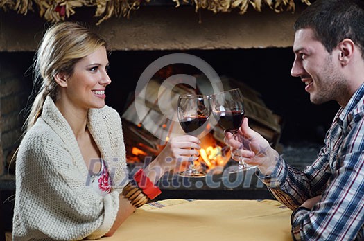 happy Young romantic couple sitting on sofa in front of fireplace at winter season in home happy Young romantic couple sitting on sofa in front of fireplace at winter season in home