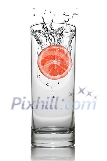 Grapefruit dropped into water glass with splash isolated on white Grapefruit dropped into water glass with splash isolated on white