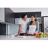 happy young couple have fun in  modern kitchen indoor  while preparing fresh fruits and vegetables food salad