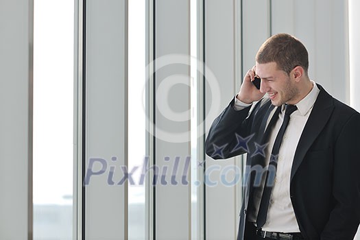 young business man talk by cellphone over bright window in big hall young business man talk by cellphone over bright window in big hall