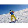 skier skiing downhill on fresh powder snow  with sun and mountains in background