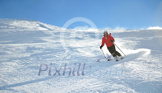 skier skiing downhill on fresh powder snow  with sun and mountains in background