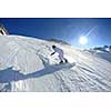 skier skiing downhill on fresh powder snow  with sun and mountains in background