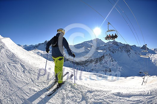 skier skiing downhill on fresh powder snow with sun and mountains in background skier skiing downhill on fresh powder snow with sun and mountains in background