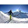 skier skiing downhill on fresh powder snow  with sun and mountains in background
