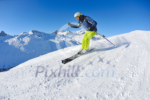 skier skiing downhill on fresh powder snow with sun and mountains in background skier skiing downhill on fresh powder snow with sun and mountains in background