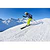 skier skiing downhill on fresh powder snow  with sun and mountains in background