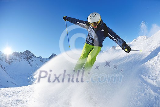 skier skiing downhill on fresh powder snow with sun and mountains in background skier skiing downhill on fresh powder snow with sun and mountains in background