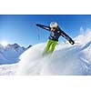 skier skiing downhill on fresh powder snow  with sun and mountains in background