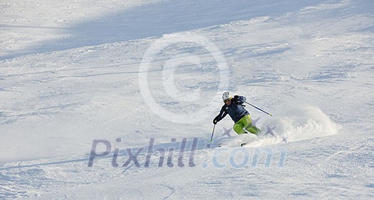 skier skiing downhill on fresh powder snow  with sun and mountains in background
