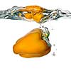 Yellow pepper dropped into water with bubbles isolated on white