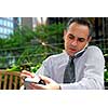Portrait of a busy businessman in the city using pda and cell phone