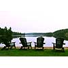 Four wooden adirondack chairs on a shore of a beautiful lake at dusk