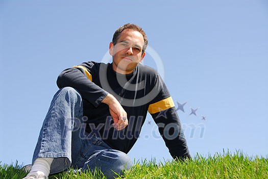 Man sitting on grass, cloudless sky background Man sitting on grass, cloudless sky background