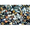 Colorful rounded pebble in clear water with sun reflections