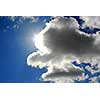 Sun coming out of the clouds in bright blue sky