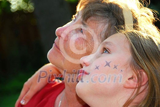 Portrait of a grandmother and granddaughter looking up with hope Portrait of a grandmother and granddaughter looking up with hope