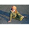 Young girl in a hat sitting on pavement, evening sun