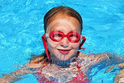Young girl in red goggles in a swimming pool Young girl in red goggles in a swimming pool