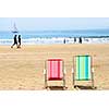 Two empty colorful beach chairs on a sandy beach