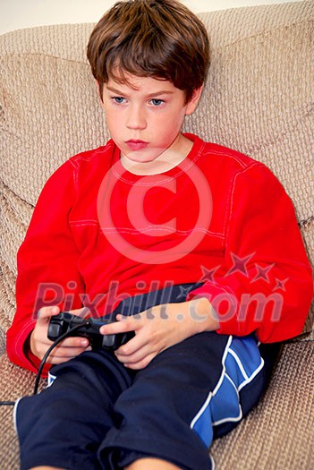 Young boy playing a video game sitting on a couch Young boy playing a video game sitting on a couch