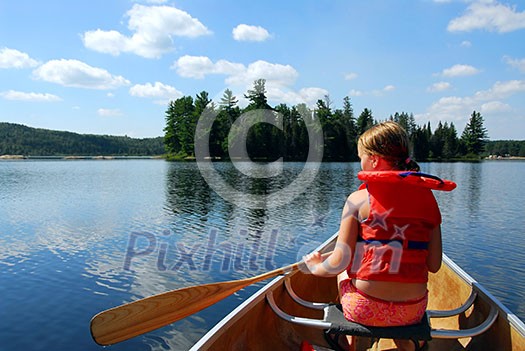 Young girl in canoe paddling on a scenic lake Young girl in canoe paddling on a scenic lake